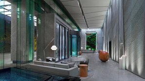 A modern indoor space with a glass wall, a seating area with cushions, a small pool, and a decorative vase. - The Westin Chongqing Liberation Square (Chongqing)