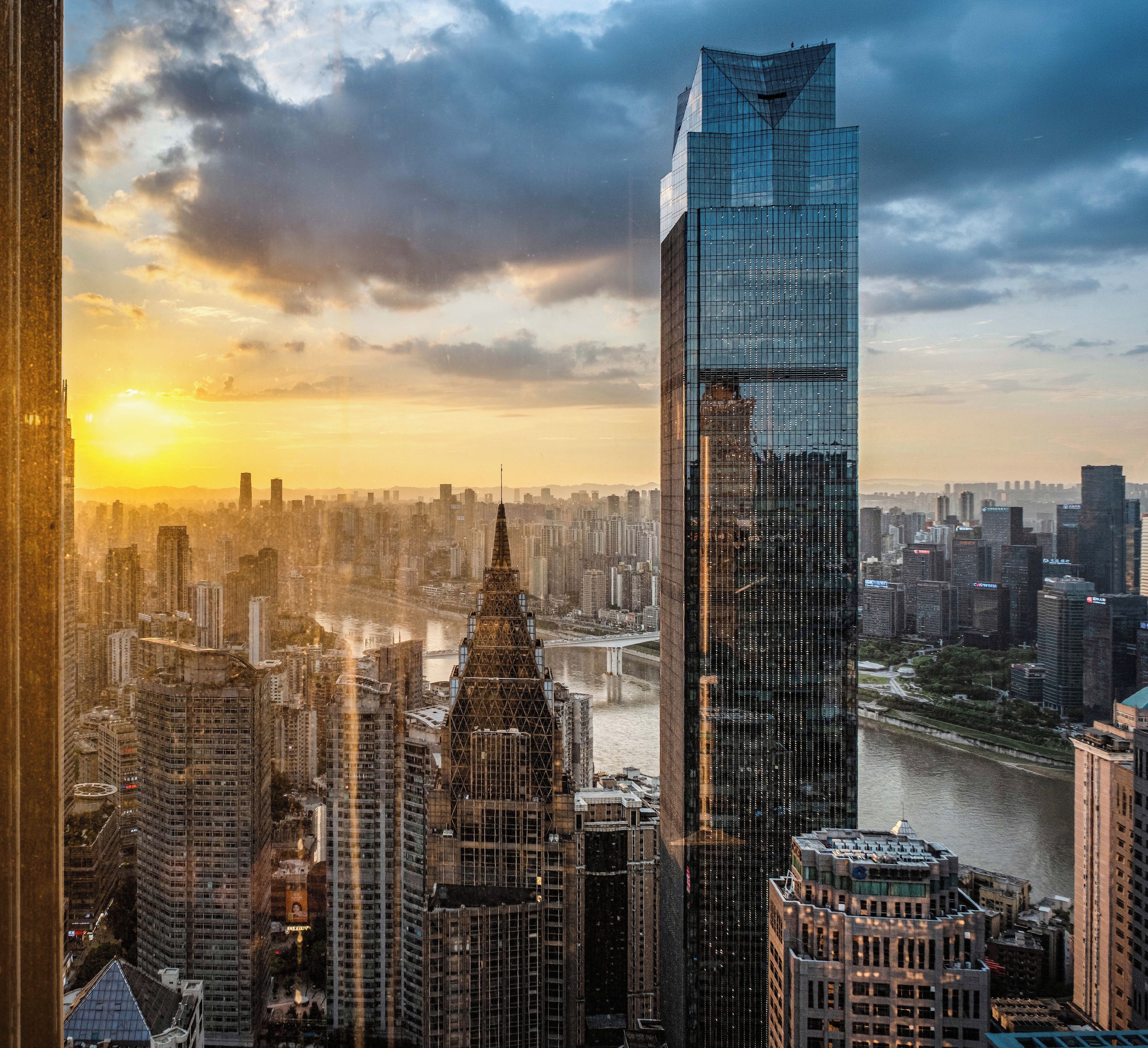 A cityscape with a prominent skyscraper, a river, and a sunset.