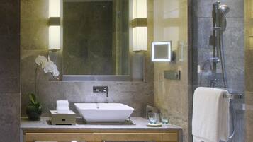 A modern bathroom with a large mirror, a vessel sink, a shower, and a towel rack.