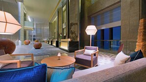 A spacious lobby with modern furniture, including sofas and chairs, a round table, and a large floor lamp. - The Westin Chongqing Liberation Square (Chongqing)