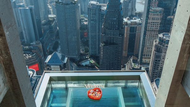 A rooftop pool with a cityscape view, a floating platform, and a swimmer. - The Westin Chongqing Liberation Square (Chongqing)
