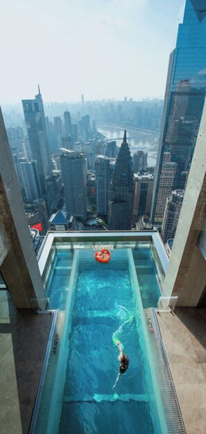 A rooftop pool with a cityscape view, a floating platform, and a swimmer. - The Westin Chongqing Liberation Square (Chongqing)