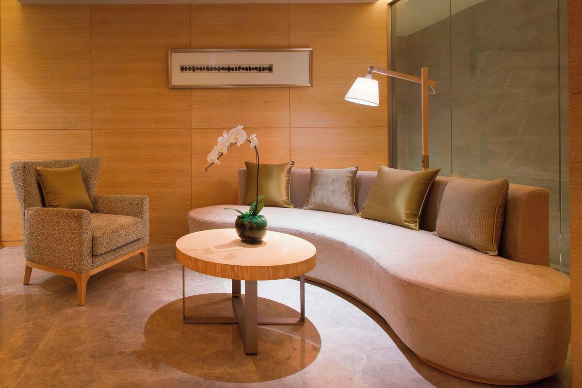 A modern living room with a curved sofa, a round coffee table, and a chair.