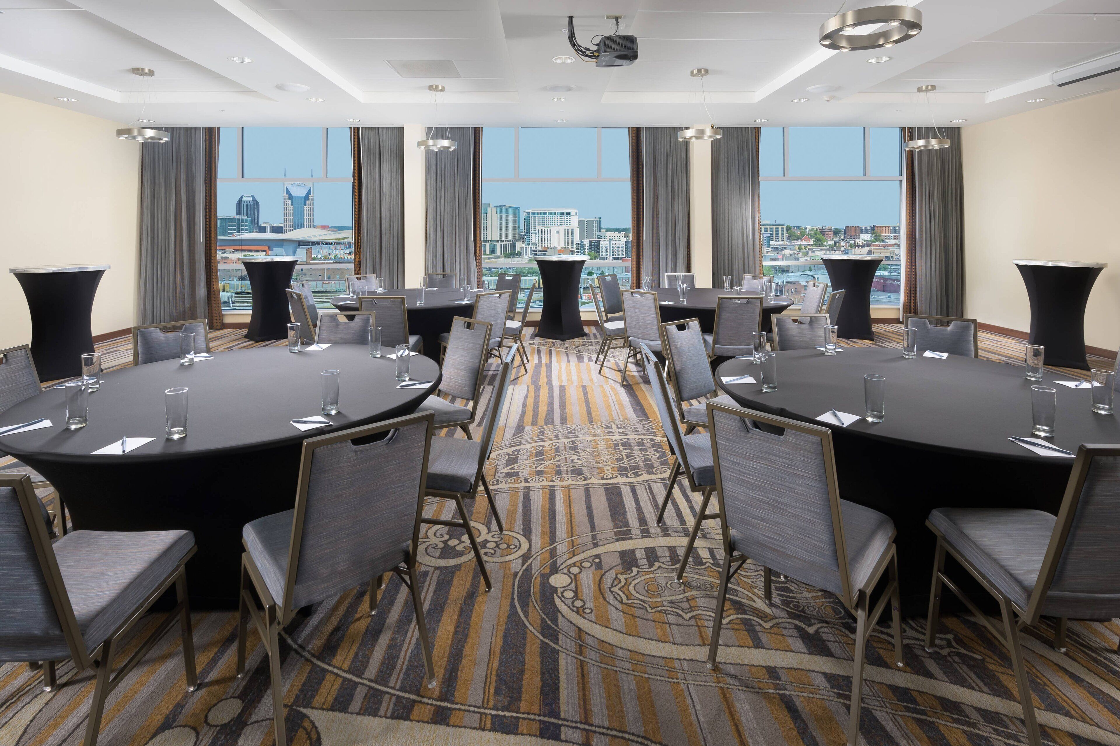 A conference room with round tables, chairs, and a carpeted floor.