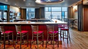 A bar area with a high ceiling, large windows, and a city view.