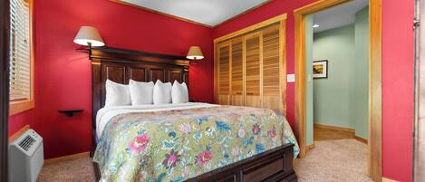 A bedroom with a wooden bed, red walls, a ceiling fan, and a wooden closet.