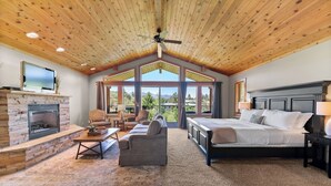A spacious bedroom with a large bed, a fireplace, and a view of the outdoors. - Mt Gardner Inn (Winthrop)