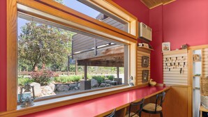 A kitchen with a large window, wooden bar counter, and stools. - Mt Gardner Inn (Winthrop)