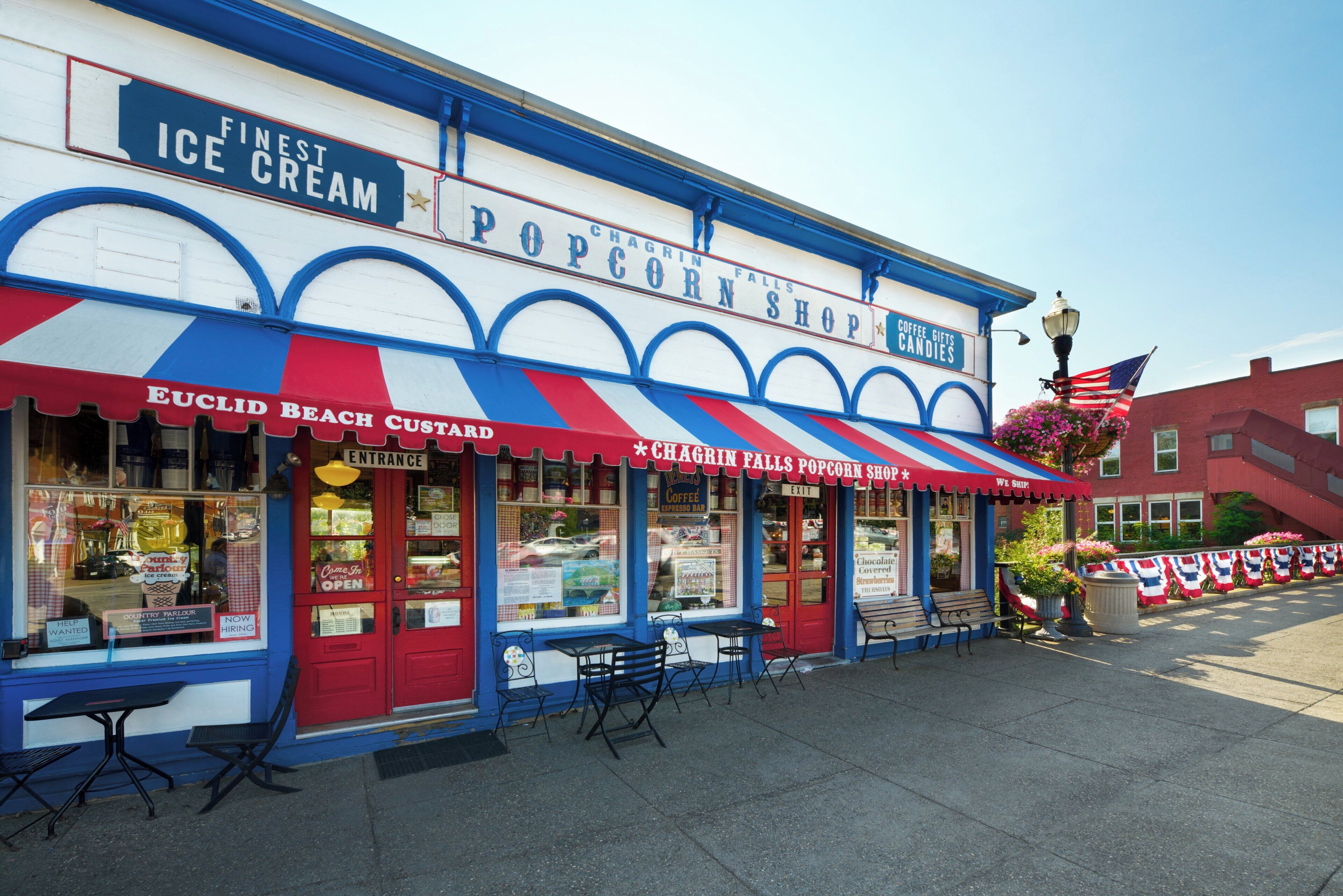 A storefront with a red and white striped awning, a sign for 'Popcorn Shop', and a blue and white facade.