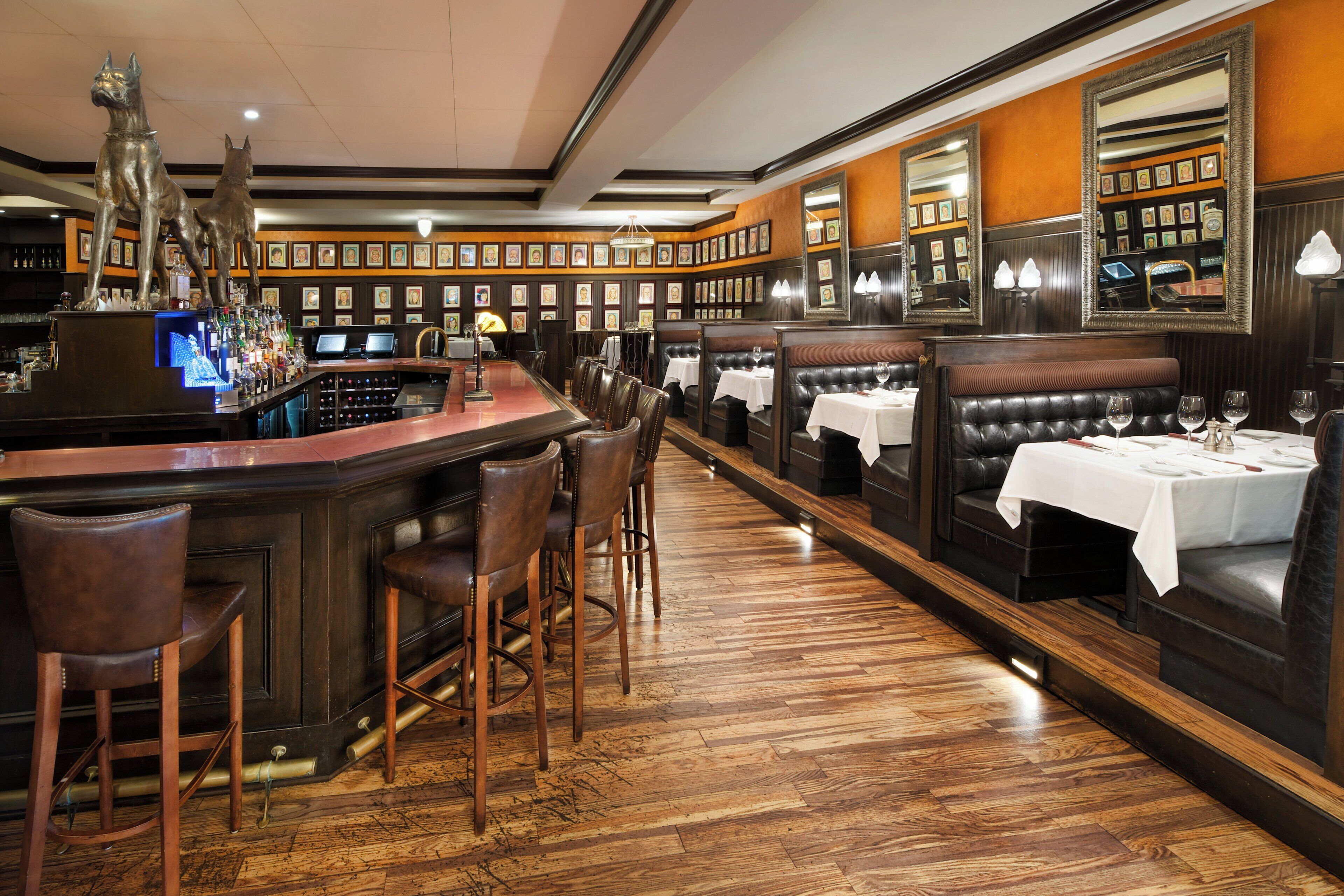 Un espace bar doté d’un long comptoir, de nombreux tabourets et d’un coin salon avec des tables et des chaises.