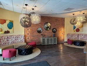 Un espace de détente moderne avec un mur en briques, des luminaires circulaires et des sièges à motifs.