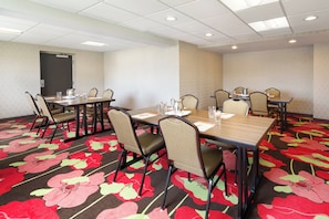 Una sala de conferencias con una larga mesa, varias sillas y una alfombra estampada con motivos florales.