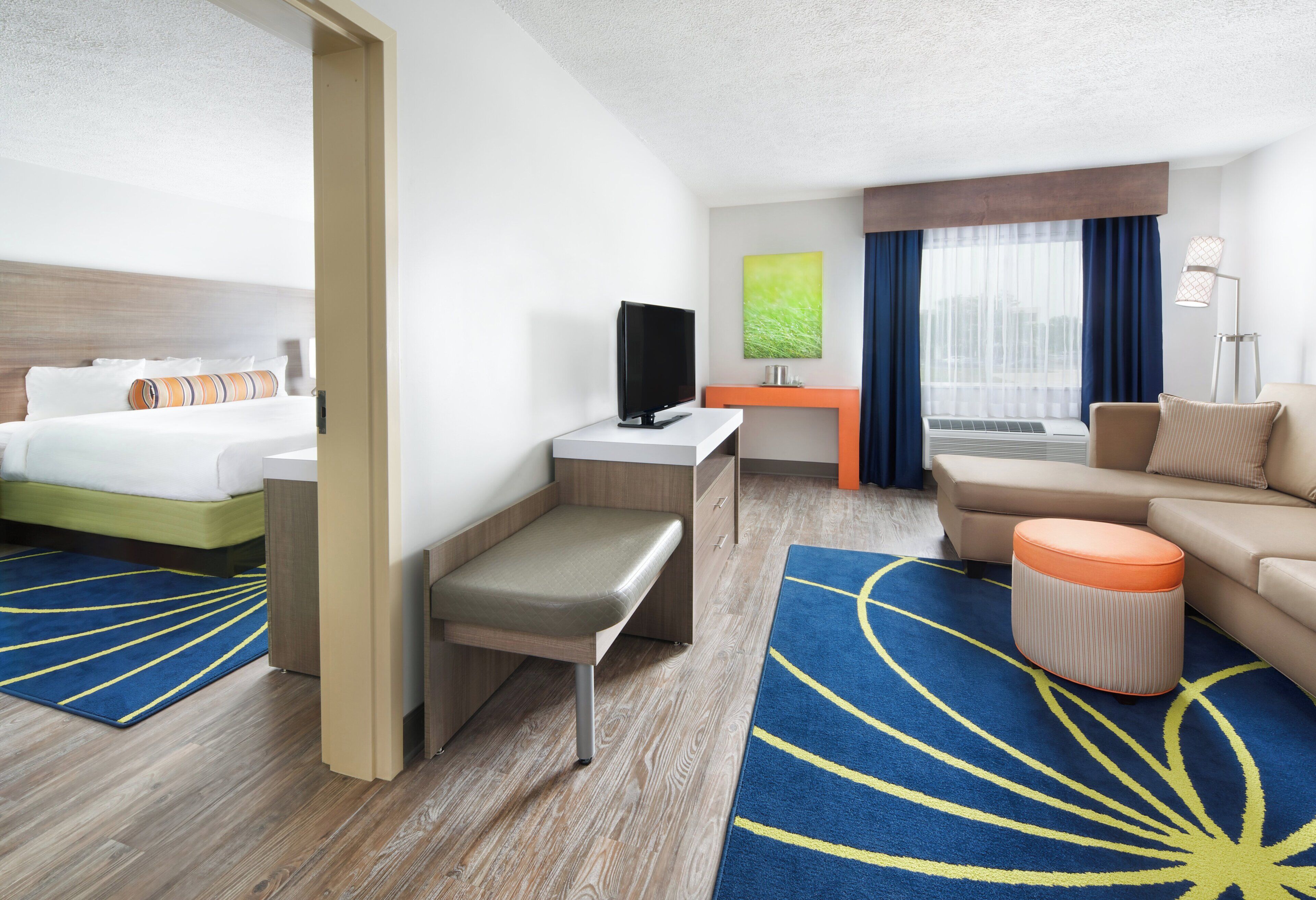 A hotel room with a bed, a desk, a sofa, and a bench.