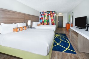 Une chambre d’hôtel avec deux lits, une télévision, un bureau et un rideau coloré.