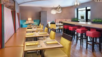 Un restaurante con cabinas, mesas altas y una zona de bar, con vista al exterior.