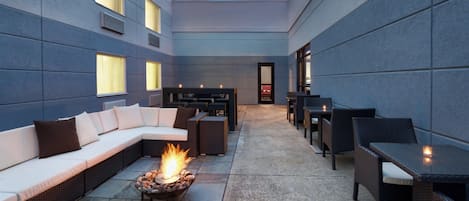 An outdoor seating area with a fire pit, sofas, and tables.