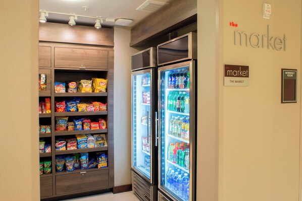 A snack and beverage refrigerator in a hotel room, with shelves stocked with various snacks and drinks.