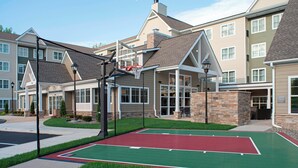 Ein Wohngebäude mit einem Basketballplatz davor.