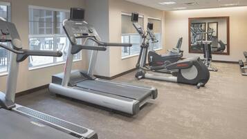 Un gimnasio con cintas de correr, elípticas y máquinas de pesas.