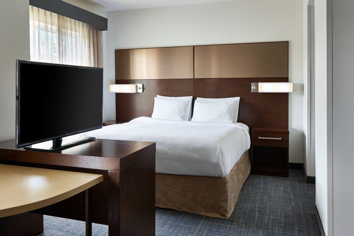 A hotel room with a bed, a TV, a desk, and a nightstand.