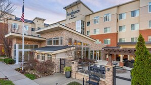 A multi-story hotel with a modern design, featuring a covered entrance, outdoor seating, and a flag. - Residence Inn Nashville SE/Murfreesboro (Murfreesboro)