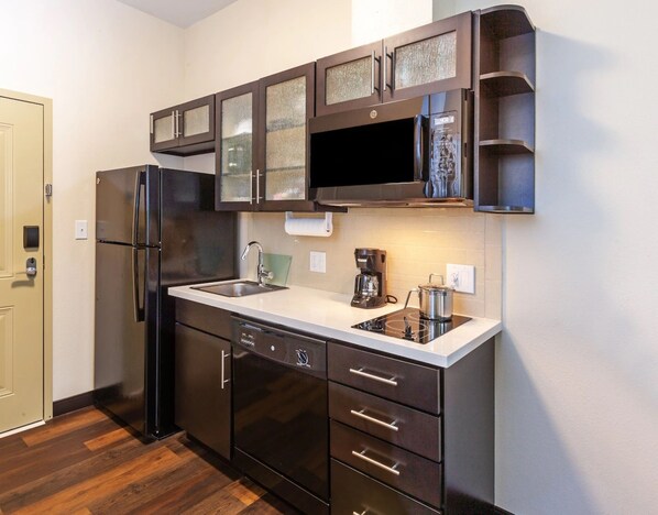A modern kitchen with a stainless steel refrigerator, a built-in oven, a coffee maker, and a microwave. - Candlewood Suites Midland SW by IHG (Midland)
