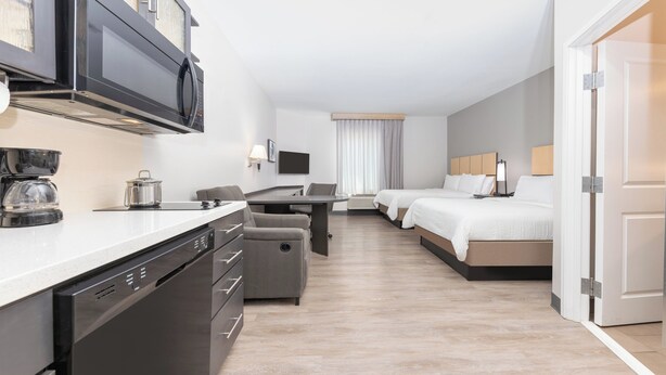 A modern hotel room with a kitchenette, a bed, a desk, and a seating area. - Candlewood Suites Midland SW by IHG (Midland)