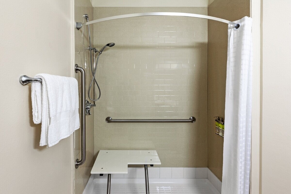 A shower stall with a grab bar, a towel rack, and a showerhead.