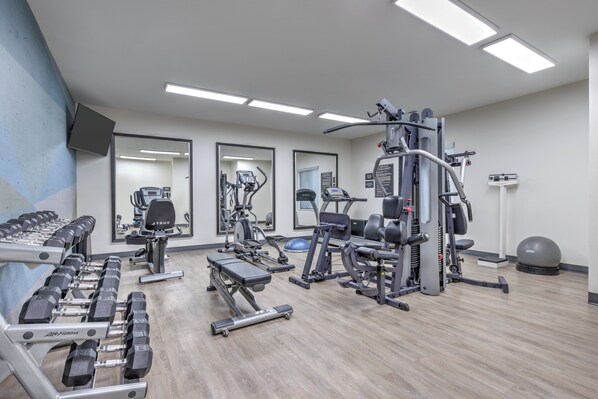 A gym with various exercise equipment, including dumbbells, treadmills, and weight machines.