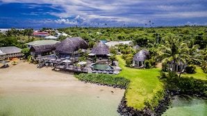 Un resort con estructuras de techo de paja, piscina y zona de playa.