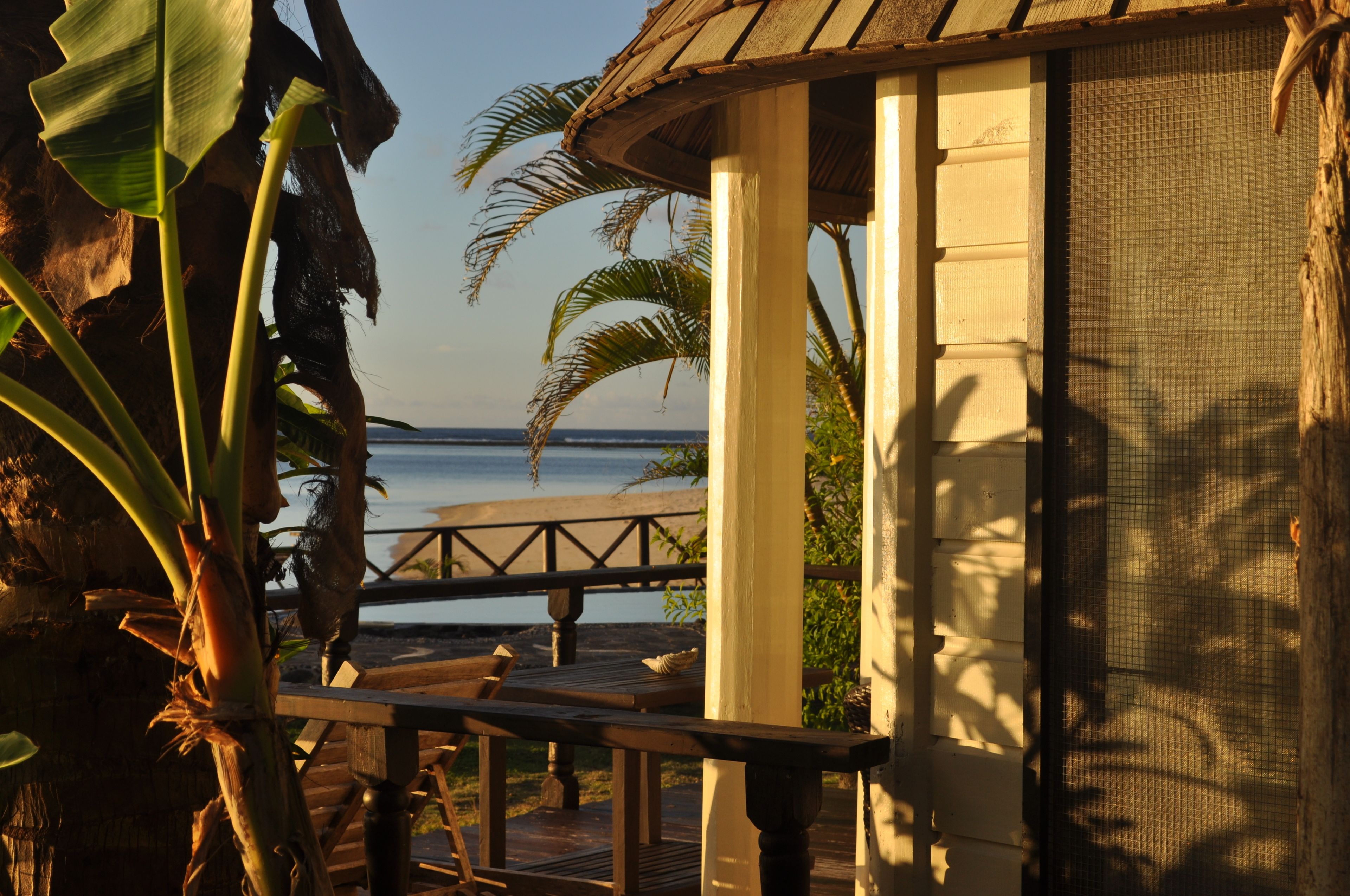 A wooden deck with a railing, overlooking a beach and ocean.
