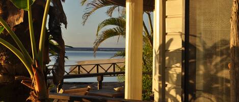 A wooden deck with a railing, overlooking a beach and ocean.