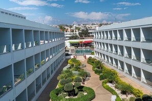 A modern building with a central courtyard featuring neatly trimmed bushes and a small pool. - Nicholas Color Hotel (Ayia Napa)
