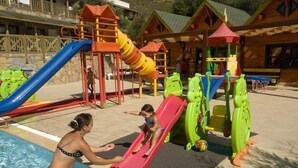 Ein Kinderspielbereich mit Rutschen und Klettergerüsten in Poolnähe.