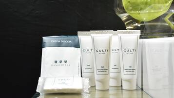 A display of hotel toiletries including a bag labeled 'CUFFIA DOCCIA' and several tubes of 'CULTI MILANO' products like shampoo and shower gel.