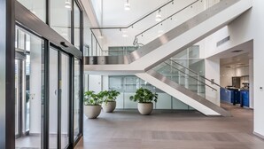 A spacious interior with a modern staircase, large windows, and potted plants. - UNA Hotels San Vitale Bologna (Bologna)