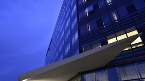 A modern building with a glass facade and a white overhang structure. - UNA Hotels San Vitale Bologna (Bologna)
