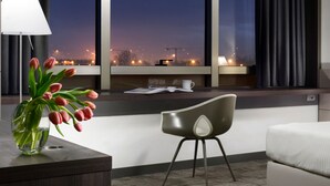 A modern hotel room with a large window, a desk with a lamp, a chair, and a bed. - UNA Hotels San Vitale Bologna (Bologna)