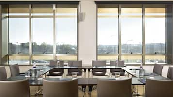 Un salón de conferencias con amplias ventanas, varias mesas y sillas.