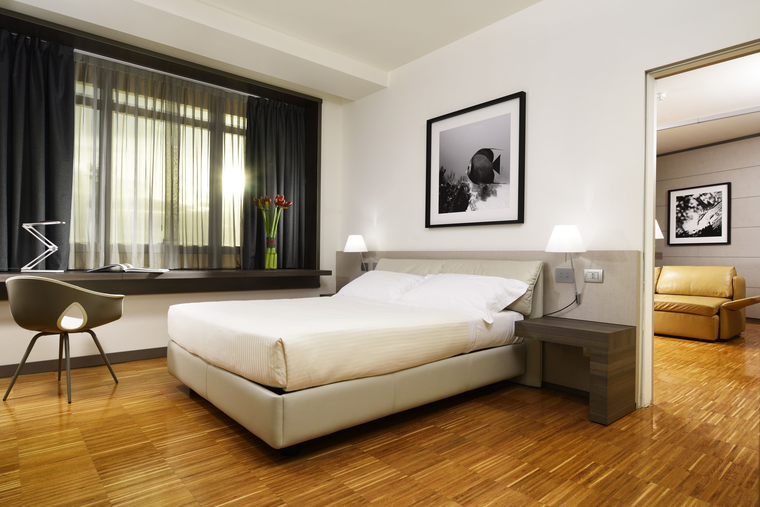 Une chambre d’hôtel moderne avec un grand lit, des tables de chevet, un bureau et une chaise.