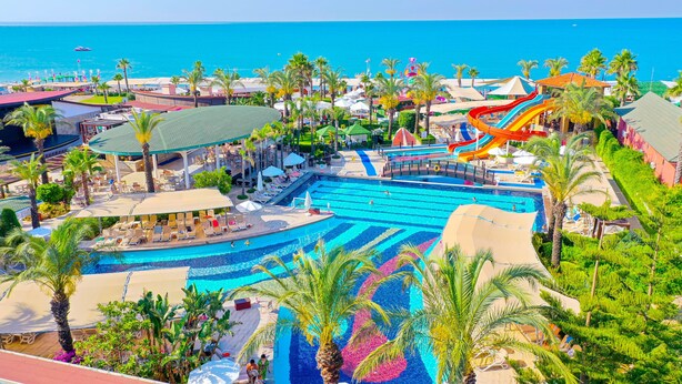 Ein Resort mit großem Swimmingpool, Wasserrutsche und Palmen.