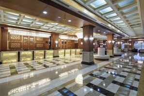 A hotel lobby with a check-in counter, large columns, and a patterned floor. - Crystal Family Comfort Collection (Serik)