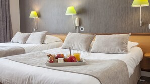 Habitación de hotel con dos camas, una bandeja de desayuno y dos lámparas fijadas a la pared.