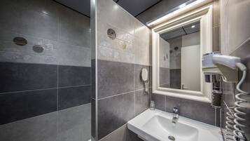 Un bagno moderno con uno specchio grande, un lavandino e un asciugacapelli.