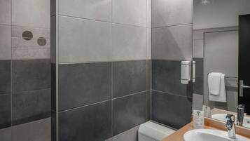 A modern bathroom with grey and dark grey tiles, a wooden countertop, a white sink, a mirror, and a towel rack.