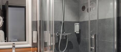 A modern bathroom with a glass shower enclosure, a sink with a wooden countertop, and a mirror with a decorative frame.