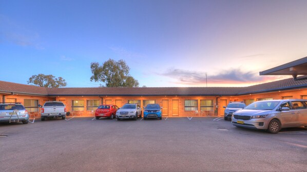 A motel with a parking lot and several cars parked in front. - Cousins Motor Inn (Inverell)