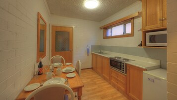 Una cocina compacta con armarios de madera, un microondas, una estufa y un refrigerador.