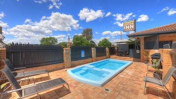 Un patio trasero con piscina, mobiliario de exterior y un letrero que indica el Cousins Motor Inn.