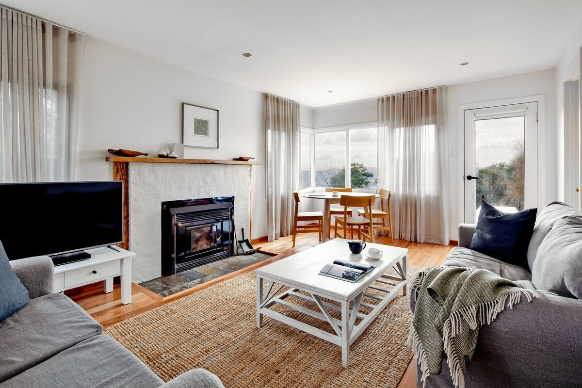 A modern living room with a fireplace, a television, a dining area, and a sofa.